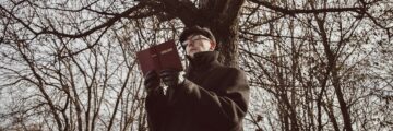 Person reading poetry under tree